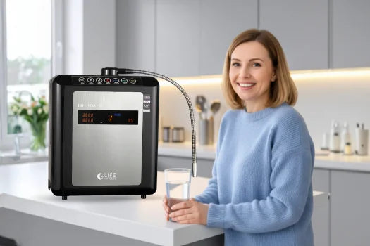 Woman holding a glass of water next to a water filter in a kitchen